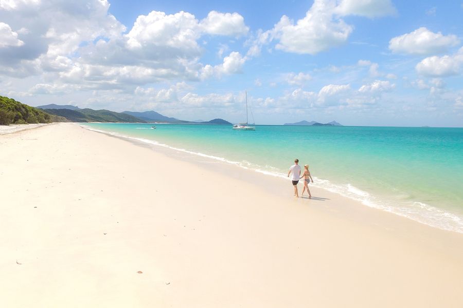 Couple walking along Whitehaven Beach