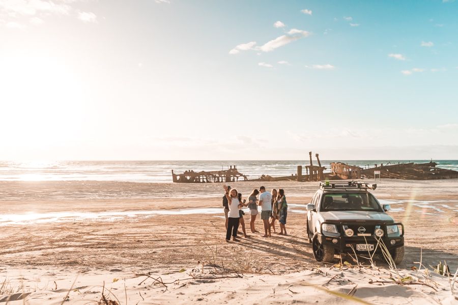 travellers gathered on the beach on k'gari near maheno shipwreck