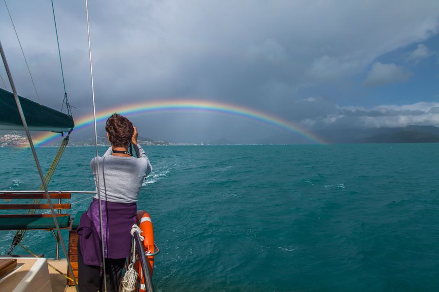 Women taking an image of a rainbow, Whitsundays