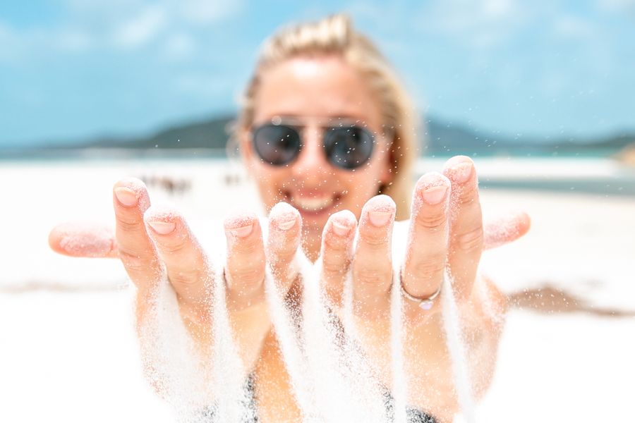 girl holding up white silica sand on whitehaven beach