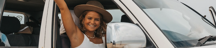 A girl wearing a hat holding her hand out of a 4WD