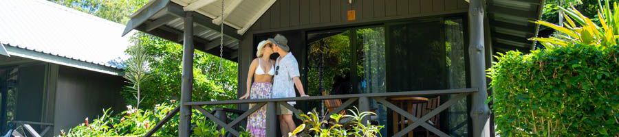 couple kissing in front of a tropical bungalow