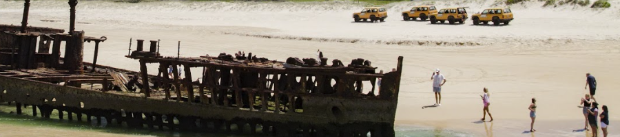 A group of people standing next to a beached shipwreck