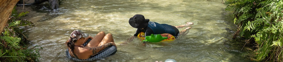 Two people on inflatables floating down a river