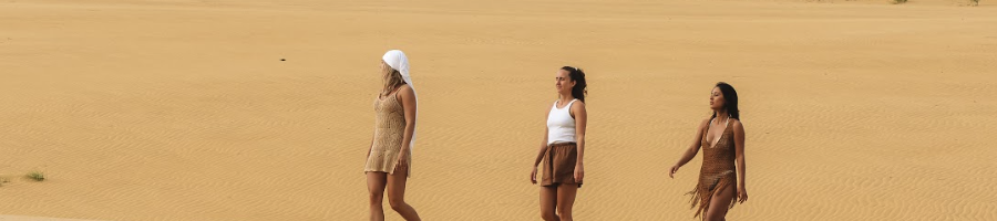 Three girls walking along a sand dune