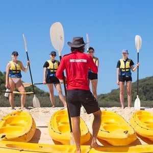 A kayak instructor for Epic Ocean Adventures with a group of tourists on the beach