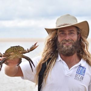 An Epic Ocean Adventures instructor holding a crab on the beach