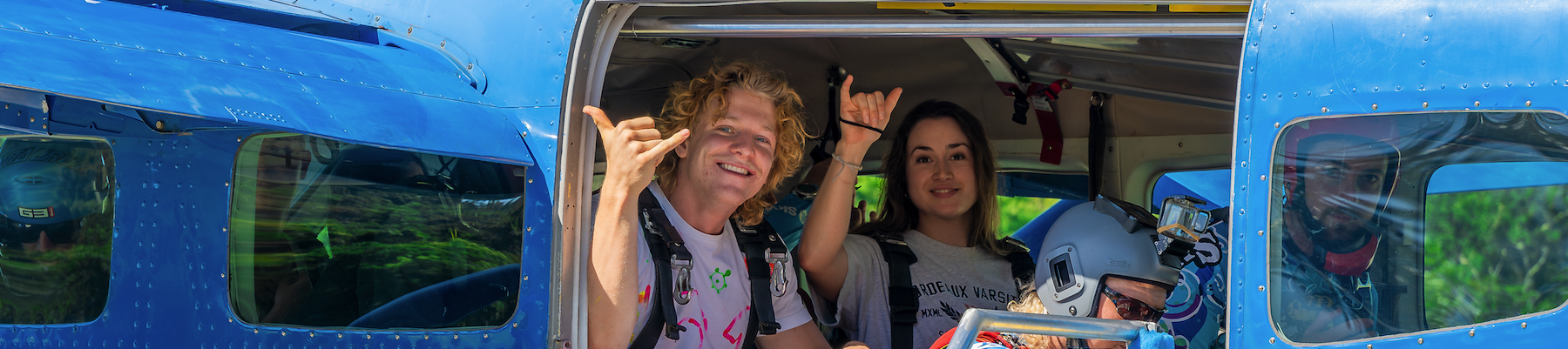 a man and woman in a skydive plane smiling at the camera