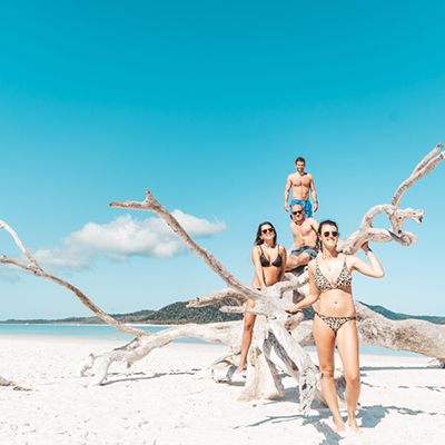 Group of four travellers on Whitehaven Beach in swimmers