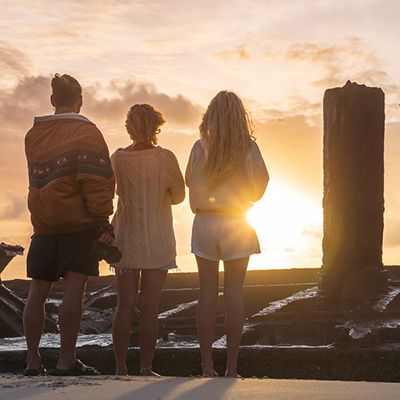 Three people looking at Maheno Shipwreck at Sunset