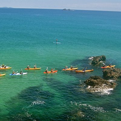 Group of friends kayaking through the ocean and reefs of Byron Bay