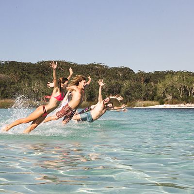 travellers jumping into the blue water of lake mckenzie