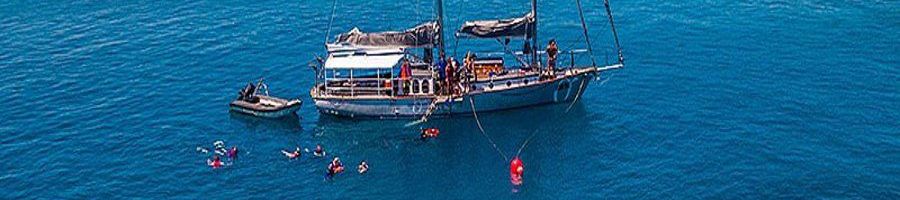 Boat in blue waters with people swimming around