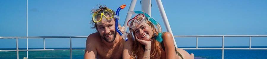 A man and a woman lying on the deck of a boat with snorkels on their heads