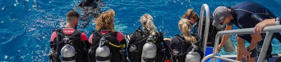 Scuba divers in their gear sitting on the edge of a boat