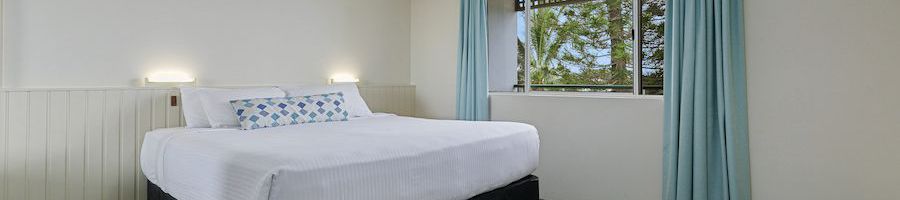 hotel bed with white linens and a window