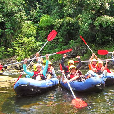 people with their paddles in the air on a river rafting tour