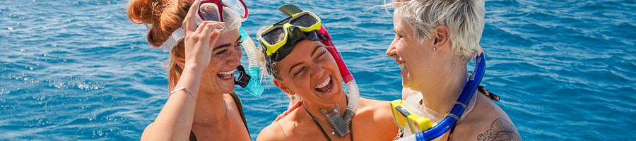 three girls laughing with snorkel gear on a boat tour