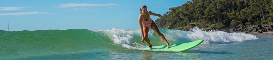 girl surfing in the turquoise ocean around noosa