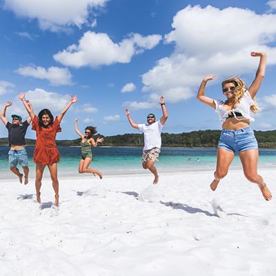 Group of backpackers jumping and smiling at Lake Mackenzie