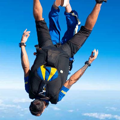 A guy and a professional skydive tandem buddy soaring through the sky
