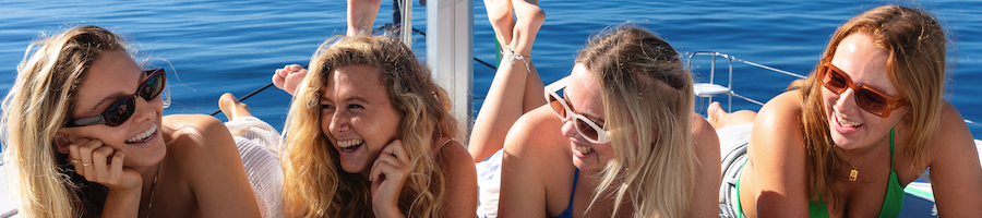 Four women on a boat laying down looking at the camera