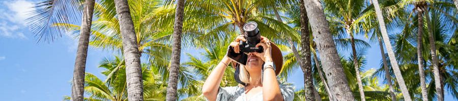 Women taking a photo at Port Douglas with palm trees in the distance.