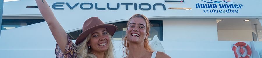 two girls smiling in front of evolution reef cruise boat