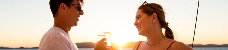 couple clinking glasses on a sunset sail in the whitsundays