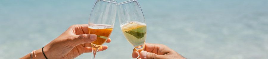 two glasses of champagne clinking over blue water