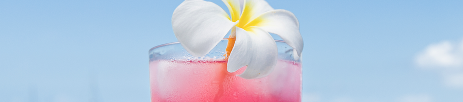 A cocktail with a frangipani flower on top