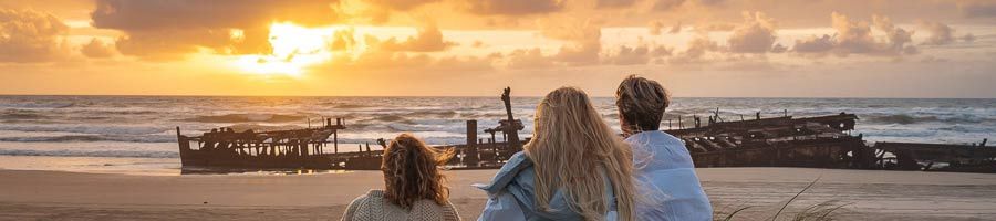 three girls watching sunrise over maheno shipwreck
