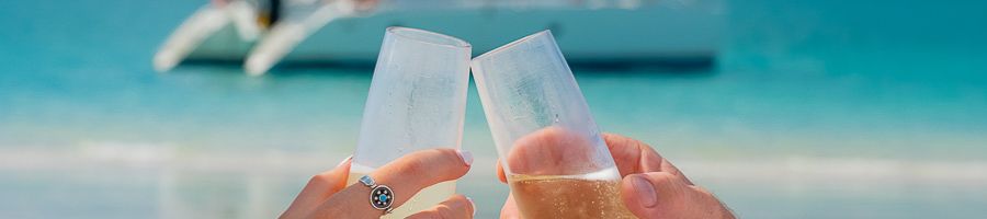 Two glasses of champagne being held up with the ocean in the background