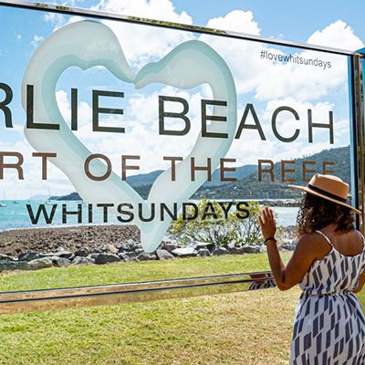 Woman standing in front of the Airlie Beach sign 