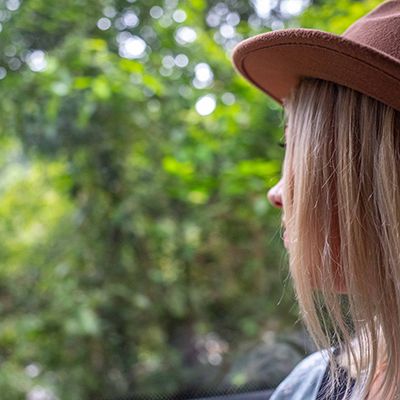 Woman in a brown hat on a bus looking at greenery