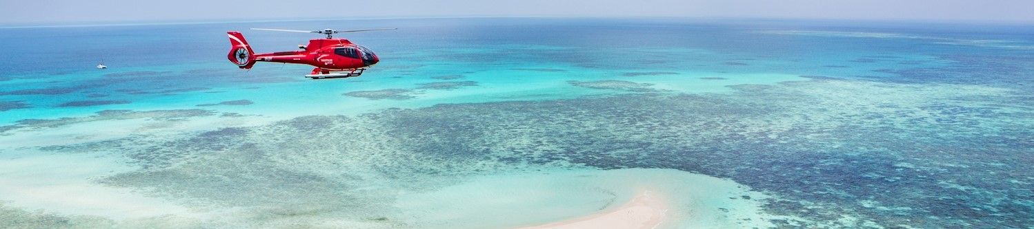 Red chopper circling over sandy cay on Great Barrier Reef