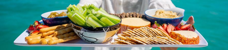 A platter of fruit and cheese held by a crew member 