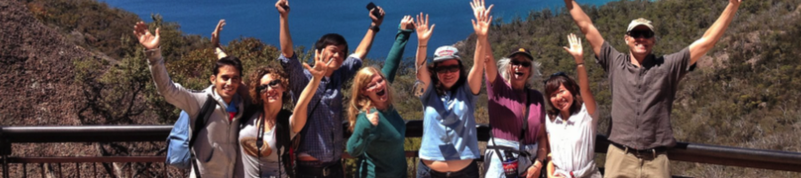 A tour group at a lookout in front of a blue water bay