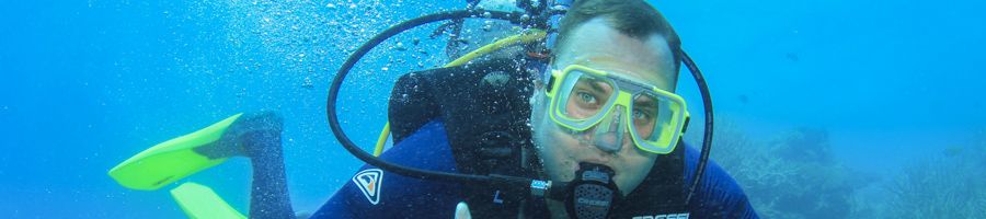 Scuba Diver closeup amongst blue waters and fish