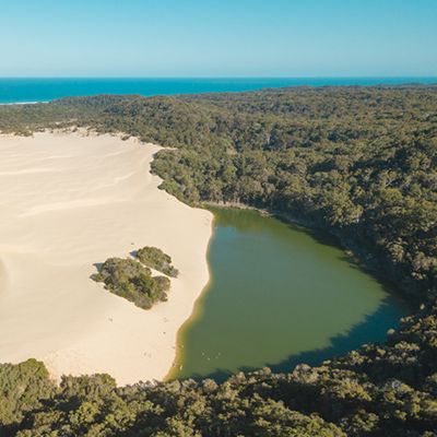 The green waters of Lake Wabby, with forest, sand and ocean drone shot