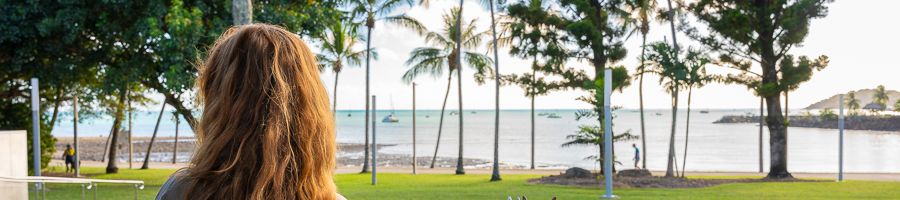 girl looking at palm trees on airlie beach foreshore