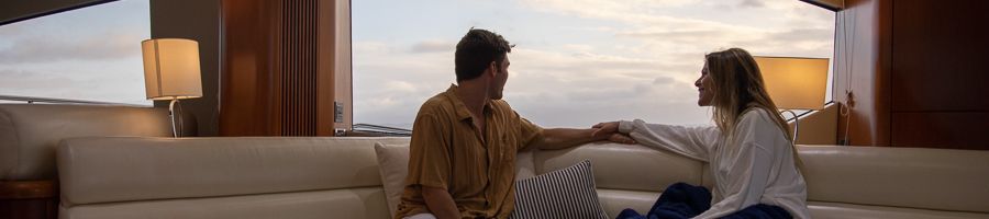 a couple inside a luxury yacht saloon with a glass of wine