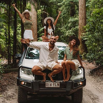 Group of backpackers sitting on a white 4wd in the forest