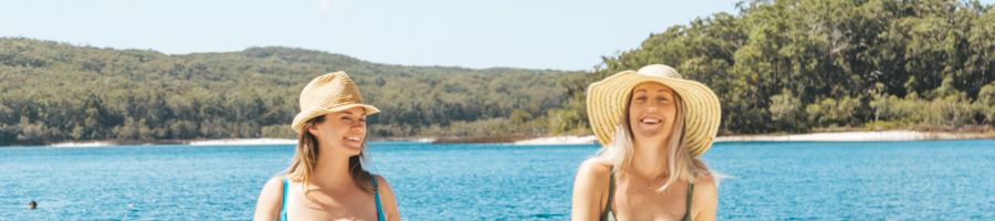 two women with hats smiling at lake mckenzie