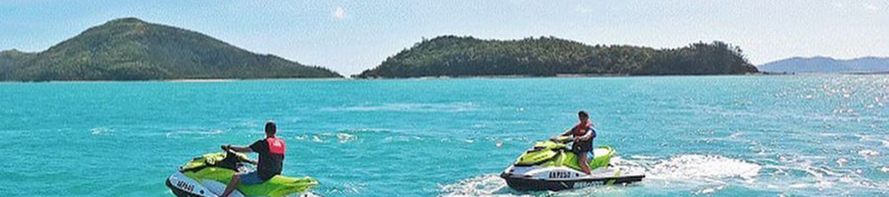 Two people zooming through waters on jet skis Whitsundays