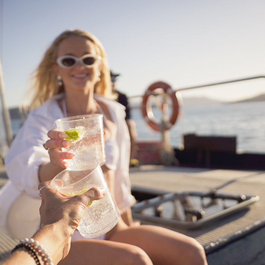 Woman cheersing a bubbly drink aboard a ship in the sun