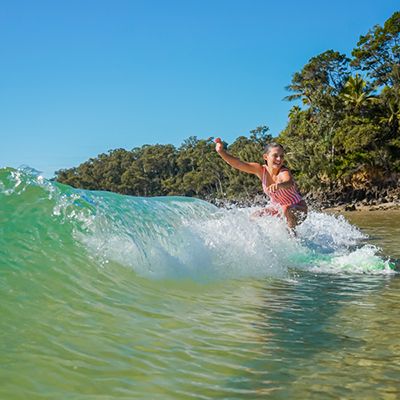 Woman on a wave on a green longboard