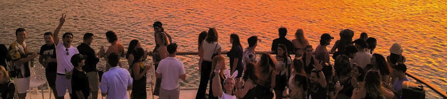 A group of people on the deck of a boat at sunset