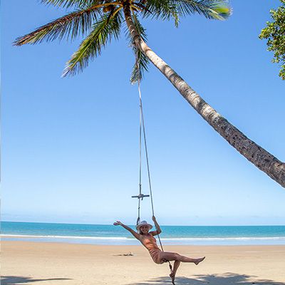 A girl on a swing hanging off a palm tree
