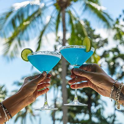 Two blue cocktails under palm trees
